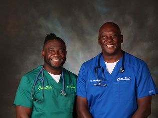Two smiling men wearing scrubs and a stethoscope against a dark background