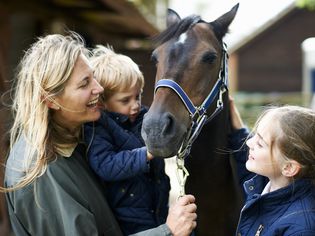 成熟的女人带着儿子和女儿抚摸着马