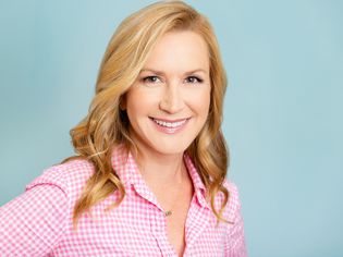 Angela Kinsey smiling on a blue background