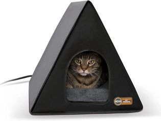 Cat resting inside K&H Pet Products Heated A-Frame Cat House displayed on white surface