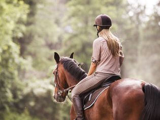 Rear view of female jockey horseback riding.