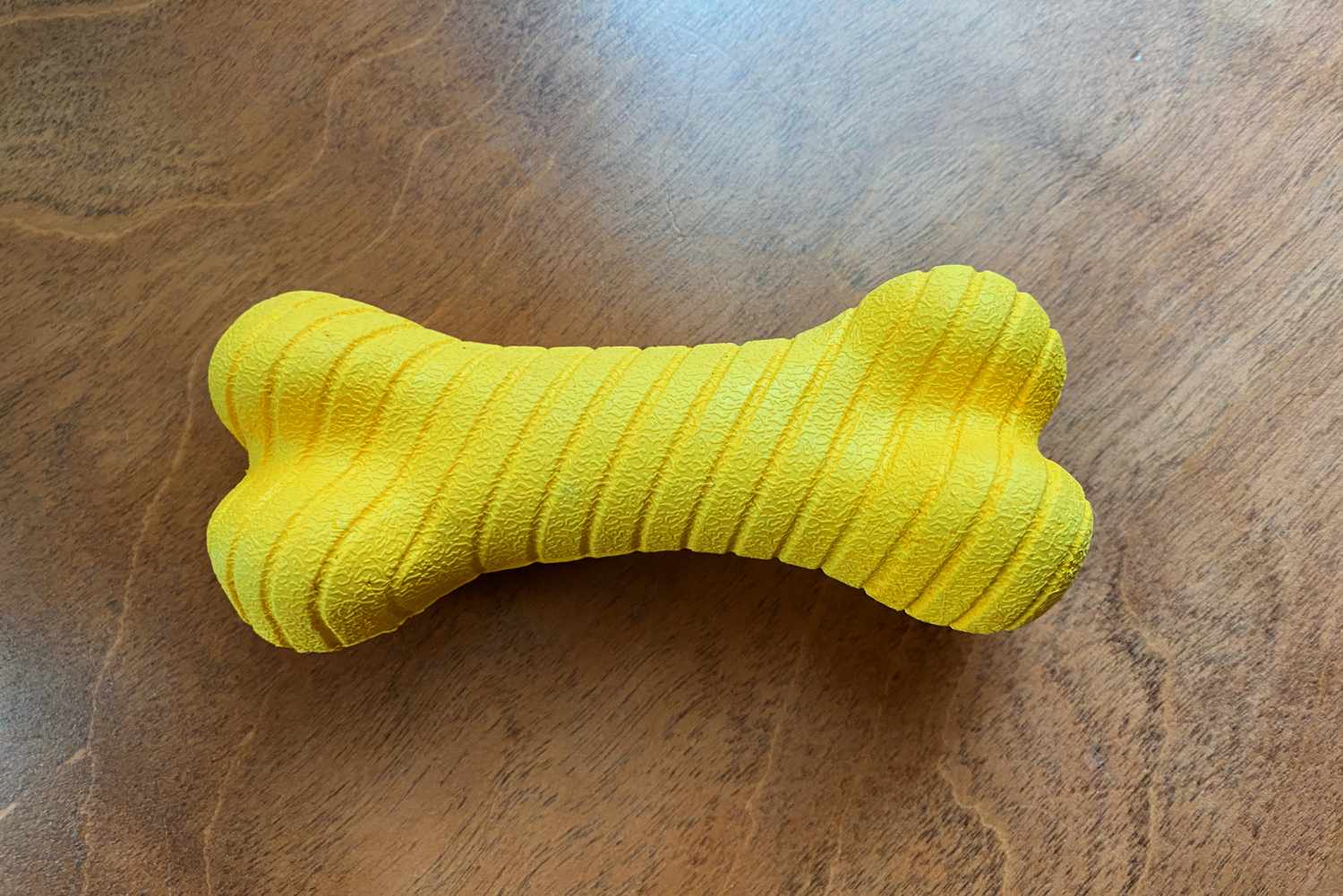 The Playology Dual Layer Bone Dog Toy sitting on a wooden surface