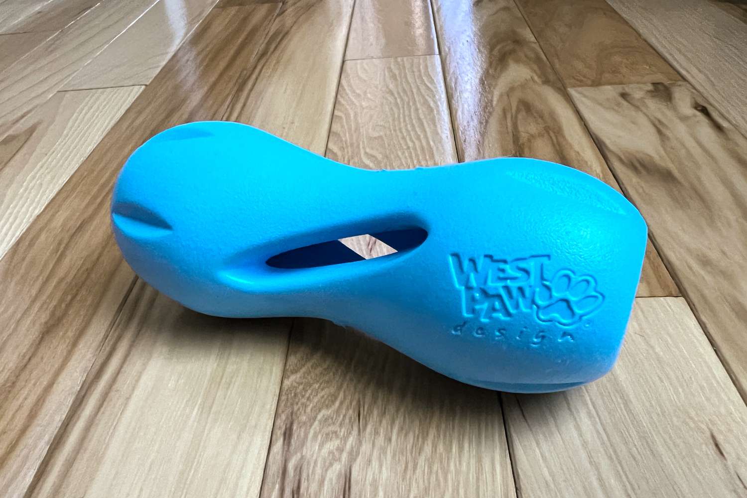 The West Paw Zogoflex Qwizl Dog Puzzle Treat Toy sitting on a wood floor