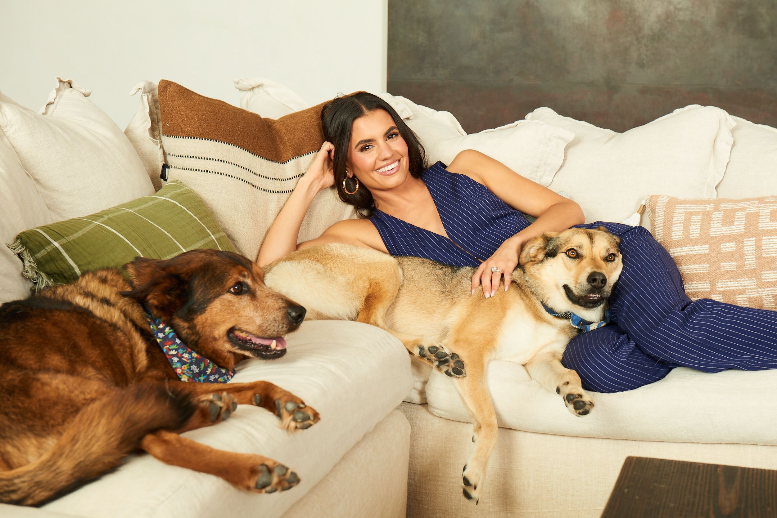 Hayley Erbert-Hough lounges on couch with her two dogs